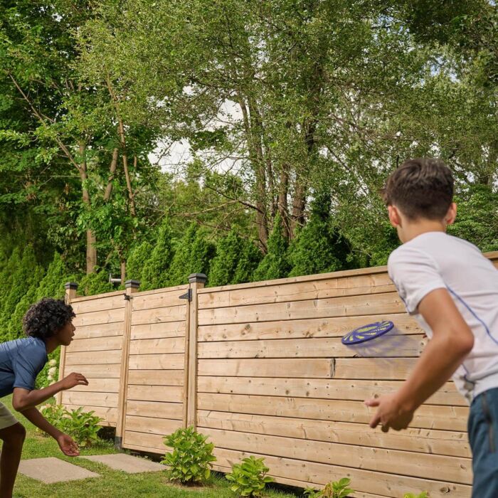 Two people playing with a frisbee in a backyard setting.